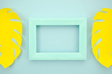 Üst görünüm siyah mavi çerçeve sarı kağıt palmiye ile süslenmiş mavi plastik bir çerçeve bırakır. Düz yatıyordu mockup