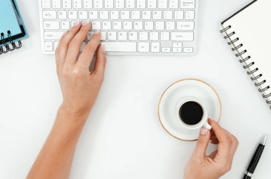 Düz yatıyordu Kadın bilgisayarda çalışıyor. Coputer klavye, oyuncak uçak, not defteri ve coffe fincan ile Ofis masası. Klavyede yazma kadın elleri