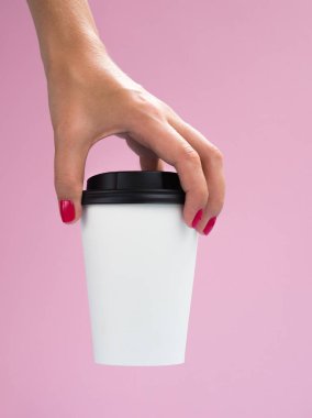 Pembe bir arka plan üzerinde izole büyük kağıt kahve fincanı ile Kadın el. Kopya alanı ile beyaz latte fincan mockup