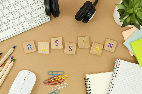 Boş spiral not defteri, klavye, kulaklık ve harflerle ahşap bloklardan yapılmış Rusça kelime ile üst görünüm masaüstü. Rusça kavramını öğrenme — Stok fotoğraf