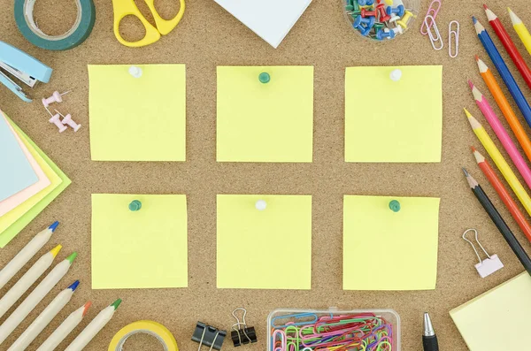 Stationary and school supplies on a cork desk. Top view frame with pinned blank sticky notes. Mockup for your text