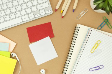 Sabit, bilgisayar klavyesi, kulaklıklar, not defterleri ve kopya sapce ile yapışkan notlar ile Düz öğrenci masaüstü yatıyordu. Üst görünüm mockup