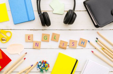 Dizüstü bilgisayarlar, kulaklıklar ve ahşap küplerden yapılmış İngilizce kelime ile üst görünüm masaüstü. Dil kavramını öğrenme