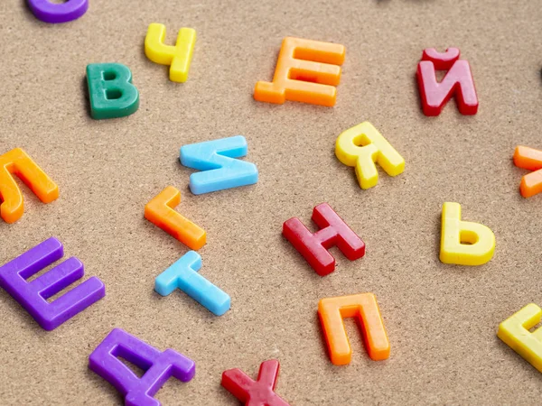 Цветные кириллические пластиковые магнитные буквы на пробковом столе. Концепция обучения языкам — стоковое фото