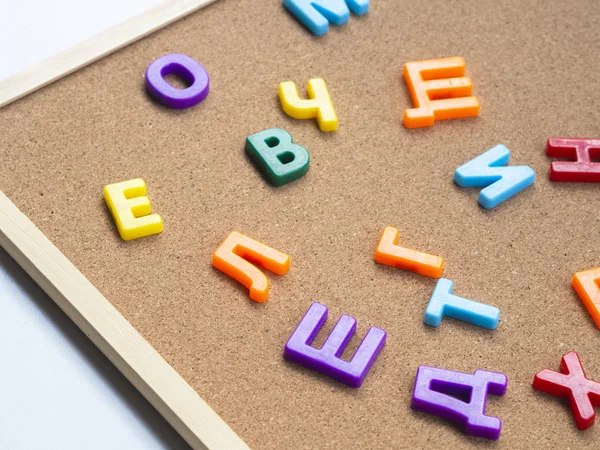 Цветные кириллические пластиковые магнитные буквы на пробковом столе с селективным фокусом. Концепция обучения языкам — стоковое фото