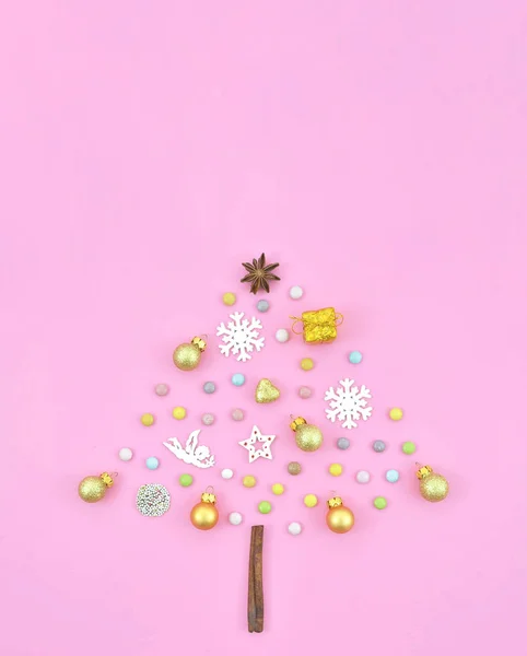 Vista superior colorido forma de árvore de Natal feito de decorações de Ano Novo em um fundo rosa. Caixa de presente, bolas, cones, lantejoulas de ouro. Flat lay Conceito de cartão de férias — Fotografia de Stock