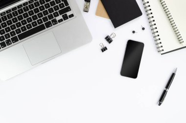 Düz ofis masası natürmort. Akıllı telefon ve spiral dizüstü bilgisayarlar ve beyaz arka plan üzerinde siyah kalem ile gümüş dizüstü bilgisayar. Kopyalama alanı ile çerçeve