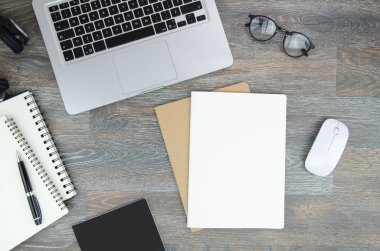 Kopya alanı ile boş kağıt A4 listesi ile üst görünüm ev ofis masası. Gümüş dizüstü bilgisayar, gözlük ve spiral not defterleri