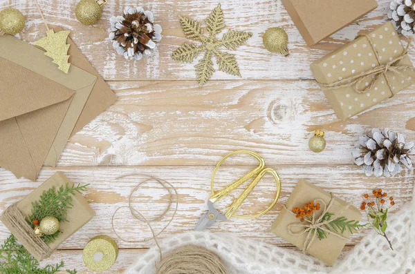 素朴な白い木製の背景に手作りの贈り物が作られた美しいクリスマスの構成。コピースペース、ひも、ギフトボックス、クラフトペーパーのオンベロープを備えたトップビューフレーム — ストック写真