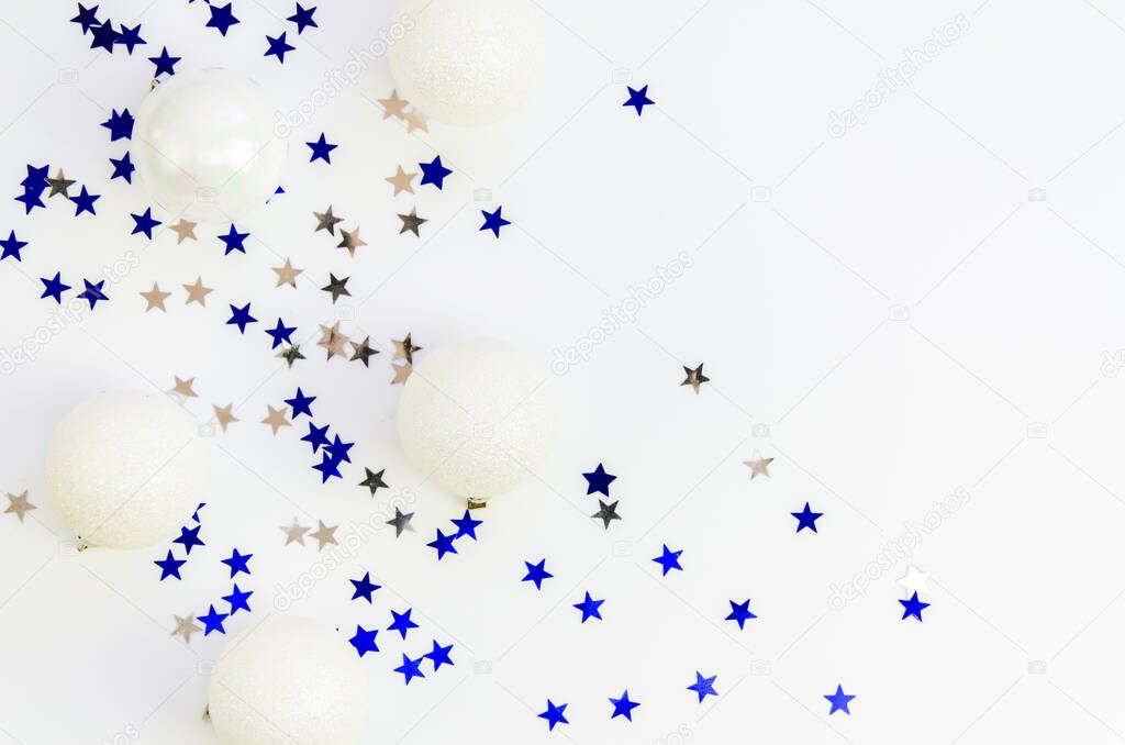 Top view white and blue Christmas background. Silver and blue xmas confetti and glass balls on a white background