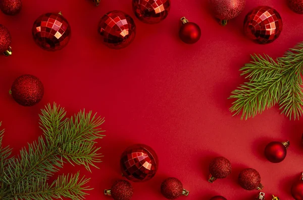 Top view Vörös karácsonyi keret háttér banner vagy promo. Zöld fenyő ágak és üveg xmas fa játékok piros alapon — Stock Fotó