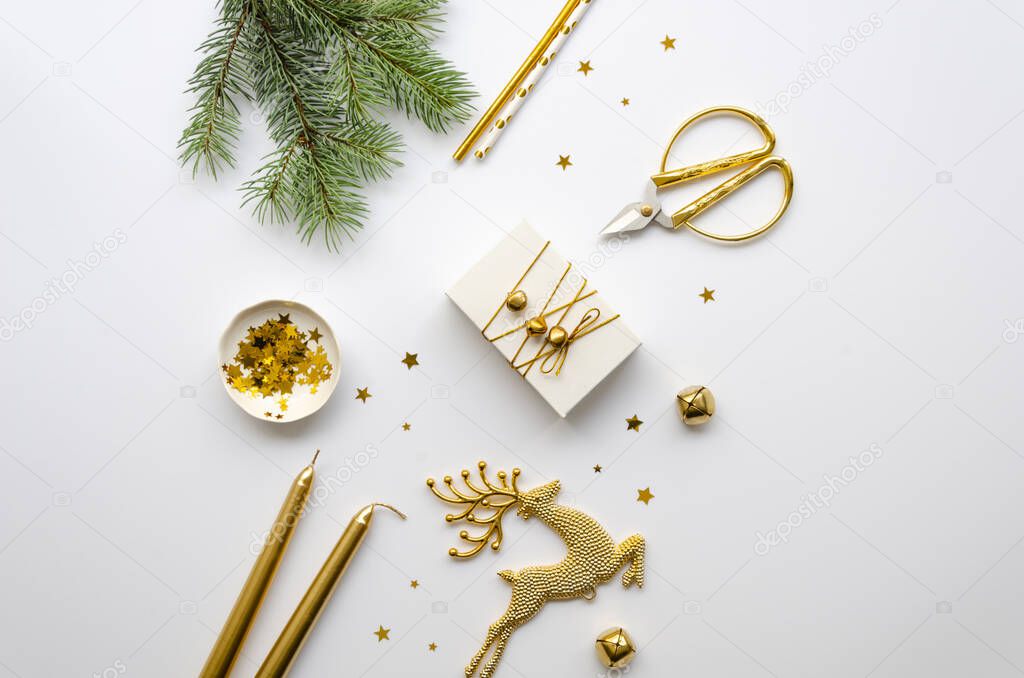 Gold Christmas flat lay. Christmas gift, scissors, gold decorations and fir branches on a white background