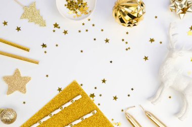 Üst manzara, beyaz masa arkaplanındaki altın Noel ağacı süslemelerinden yapılmış Noel çerçevesi. Mutlu Yıllar metni için kopyalama alanı olan tatil arkaplanı