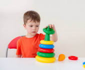 Játékok az önfejlesztés a gyermekek. A finom motoros készségek fejlesztése. Összpontosított fiú gyűjt egy színes piramist.