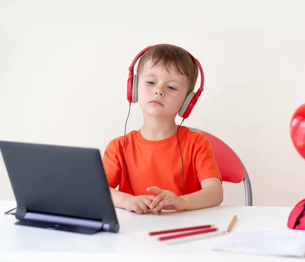 Online onderwijs voor kinderen concept. Gerichte jongen met hoofdtelefoon zelf-isolatie met behulp van tablet voor e-learning — Stockfoto