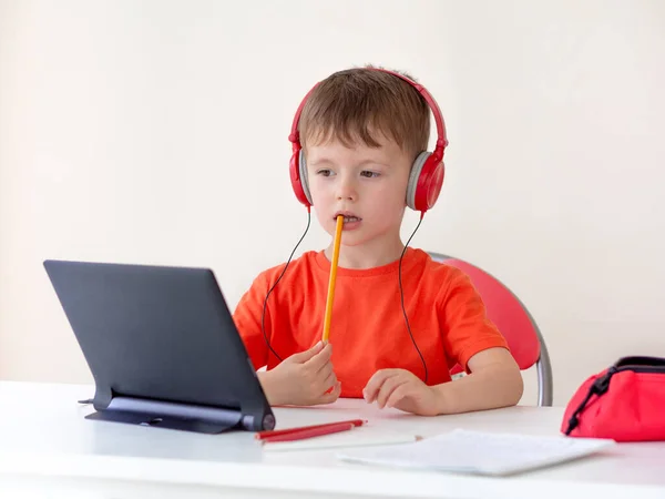 E-öğrenim online eğitim. 5 yaşındaki bir öğrenci internetten tablet kullanarak bir kalem kemiriyor. Evde eğitim — Stok fotoğraf