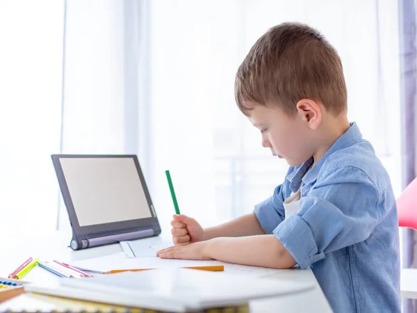 Homeschooling, E-learning online education mockup. Tablet for video lessons with a blank screen. Focused kid learning to write