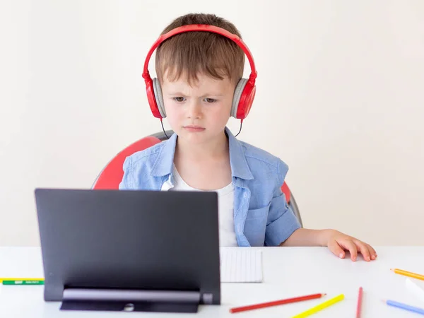 Online schoolconcept. Geconcentreerde jongen draagt koptelefoon luistert naar webcast met leraren les op een tablet pc — Stockfoto
