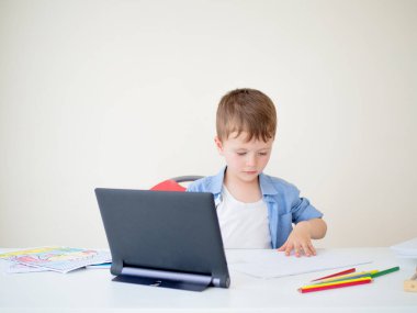 İlkokul öğrencileri için çevrimiçi dersler. Çocuk evde bir tablette internet yayını dersi seyrediyor ve resim yapmayı öğreniyor.