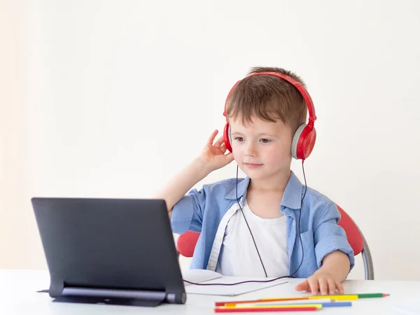 Anaokulu çevrimiçi ders uygulaması. 4 yaşındaki bir çocuk kulaklık takıyor ve bir tabletten online ders izliyor. — Stok fotoğraf