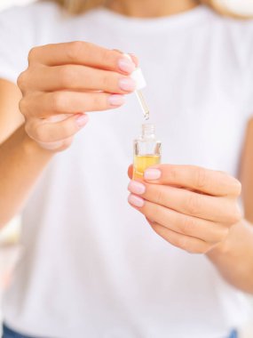 Kadınlar açık bir şişeyi kozmetik yağıyla tutarlar. Beyaz bir tişört giy. Logonuz için yer