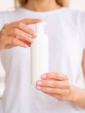 Köpük ya da temizleyici köpük için plastik pompa şişesi. Kadın elleri logo için yeri olan temiz kavanozu tutar. Dikey yüz temizleme kozmetik modeli