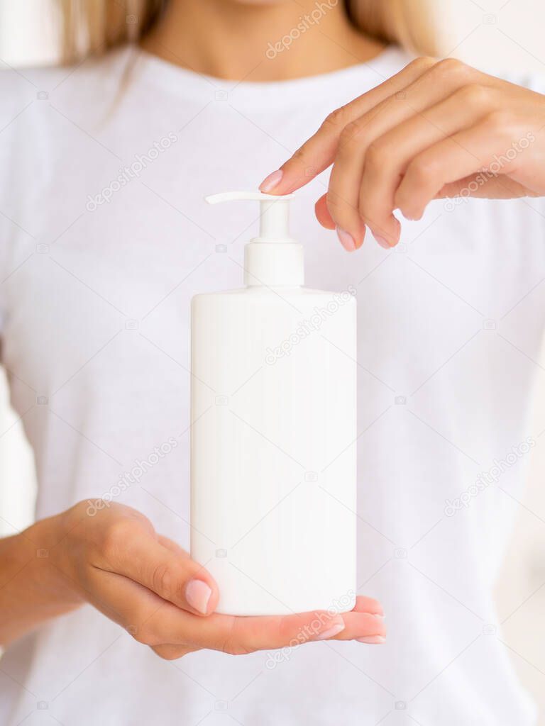 Plastic pump bottle for liquid soap or gel. Woman hold White clean jar with space for logo. Vertical front view mockup