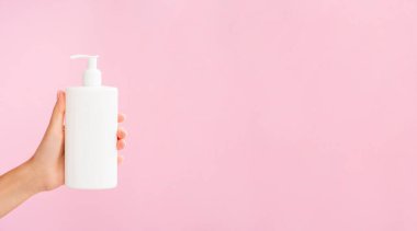 Hijyen Ürünleri Modeli. Sıvı sabun ya da jöle için plastik pompa şişesi. Beyaz kavanozu pembe arka planda tutan kadın. Reklam metni için alanı kopyala