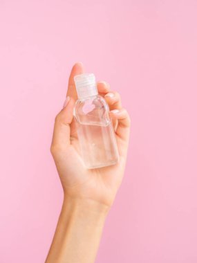 Gül suyu kozmetik modeli. Kadın eli pembe arka planda gül suyu olan şeffaf bir kavanozu tutuyor. Logo markantanız için boşluk kopyala