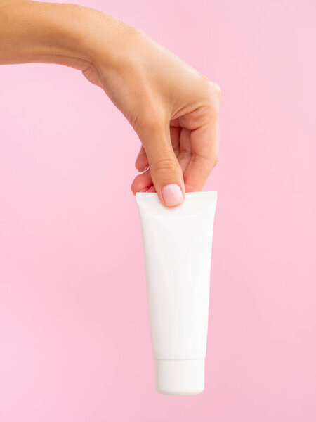 Close up cosmetic product banner mockup. A womans hand holds a white jar of hands cream. Copy space for logo