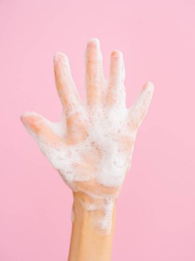 El yıkama konsepti. Pembe arka planda izole edilmiş kadınsı sabunlu avuç içi. Düz yatıyordu