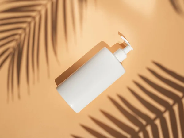 White clean tanning Lotion or Sunscreen cream bottle for package mockup. Palm leaves shadows and beige background. Minimal summer skin care and Sun protection concept. Top view with space for logo