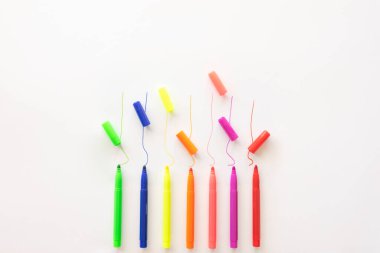 Okula geri döndüm. Beyaz kağıt arkaplanda renkli çizgileri olan çok renkli keçeli kalemler