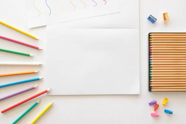 Schulattrappe. Bleistifte umranden leeres Album zum Zeichnen auf dem weißen Tisch. Draufsicht mit Kopierraum — Stockfoto
