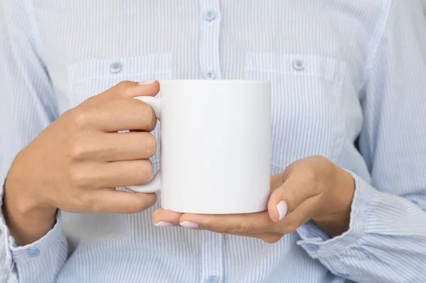 Taza de cerámica blanca maqueta. Chica lleva camisa azul sostiene una taza de cacao. Espacio para tu marca de texto — Foto de Stock