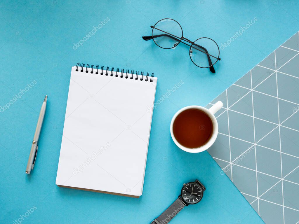 Hipsters to-do list mockup. Creative design table with notebook, glasses, tea and watch. Copy space colored background. Top view