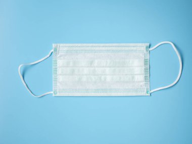 Covid-19 önleme konsepti. Tek tıbbi koruyucu maske. Renk arkaplanı üzerinde düz yatıyordu