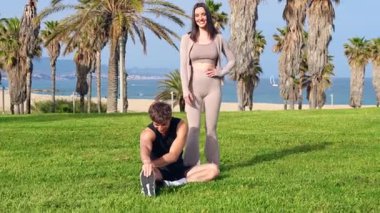 Atletik çift birbirine sarılıyor ve neşeli bir selfie çekiyor. Deniz kenarındaki yemyeşil bir palmiye bahçesinde kırmızı bir akıllı telefon ile yaz aşkını, sporu, seyahat anılarını ve canlı açık hava yaşam tarzını kutluyorlar..