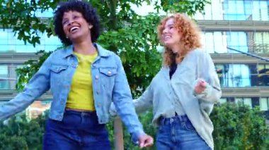 Şehir parkında dans eden ve birlikte eğlenen çok ırklı bayan arkadaşlar, neşeli yaşam tarzı, eğlence, müzik ve arkadaşlık konsepti.