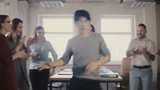 Gelukkig Aziatische jonge zakenman dansen op toevallige kantoor feest. Japanse werknemer viert de overwinning met collega's 4k. — Stockvideo