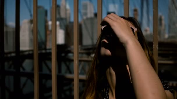 Gros plan portrait d'une heureuse femme caucasienne aux lunettes de soleil regardant dans le ciel, profitant d'une journée ensoleillée au Brooklyn Bridge 4K . — Video