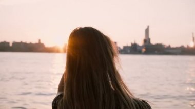 New York City'de günbatımı 4 k seyir su rüzgarda uzun saçlı güzel Avrupa kız duruyor.