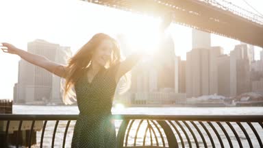 Kamera yavaş hareket gülümseyen nehir setin çit yükseltilmiş kollu yakınındaki iplik mutlu heyecanlı oynak genç kadın.
