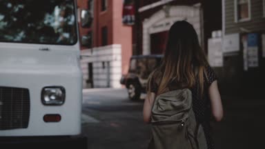 Beyaz minibüs, boş zaman yürüyüş yavaş zevk yakınındaki karşıya sırt çantası ile genç kadın turist kamera izler.