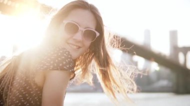 Gün batımı New York sahne kameraya gülümseyen güneş gözlüğü mutlu Avrupa kadın turist close-up ağır çekim.