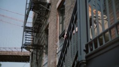 Kırmızı tuğla bina, ağır çekim üzerinde yürüyen eski merdivenlerden aşağı gidiş sırt çantası ile arkadan görünüşü güneş gözlüklü genç kız.