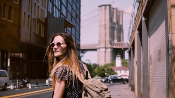 Cámara sigue feliz chica caucásica en gafas de sol de moda con el pelo soplando en el viento en la ciudad de Nueva York cámara lenta — Vídeos de Stock