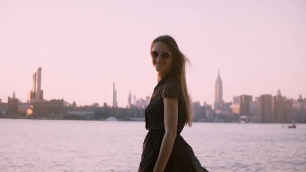 Европейская женщина в солнцезащитных очках, улыбаясь, смотрит в камеру, наслаждаясь летним закатом, замедленной съемкой. . — стоковое видео