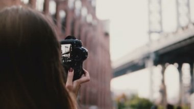 Arkadan görünüm tanınmaz halde kadın kamera ile New York City 4 k Dumbo District Brooklyn Köprüsü'nün fotoğraflarını çeker.