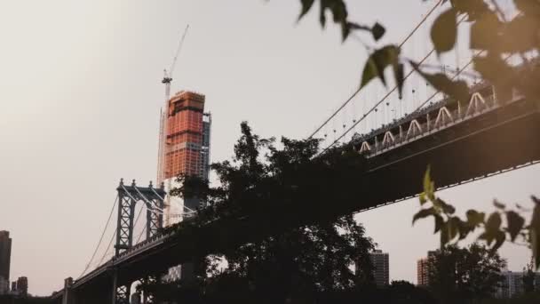 Mooie lage hoekmening van Manhattan Bridge in New York, bomen en wolkenkrabber in aanbouw in achtergrond 4k. — Stockvideo